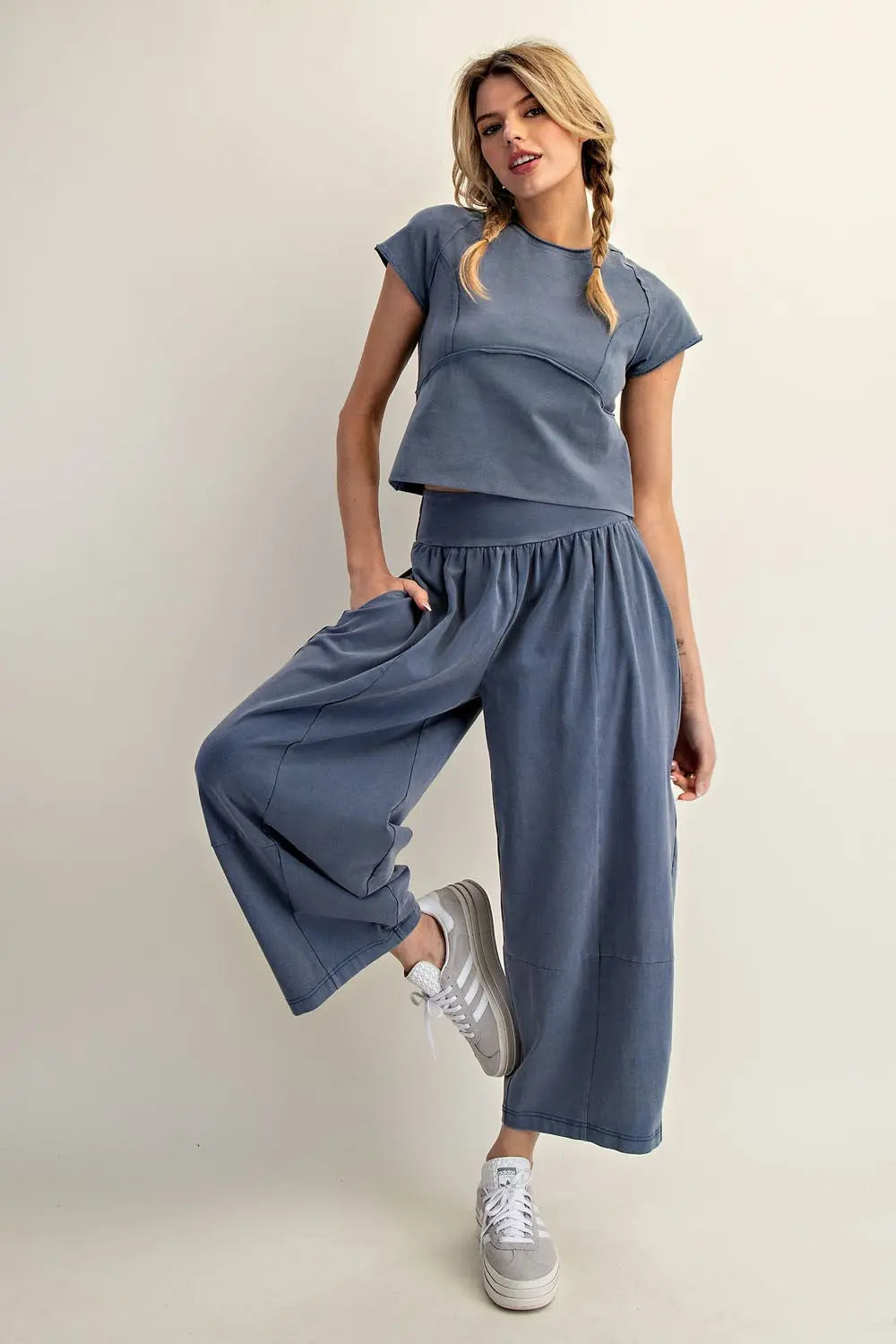Woman wearing a blue outfit with wide-leg pants and a matching top on a plain background