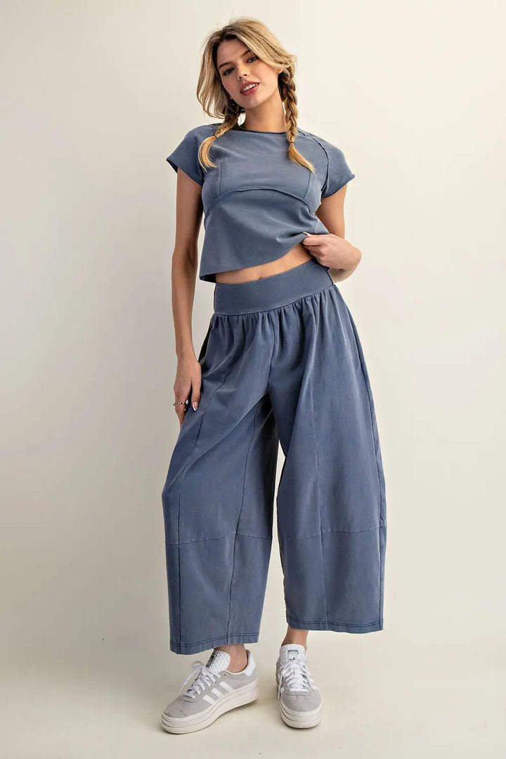 Woman wearing a blue outfit with wide-leg pants on a plain background