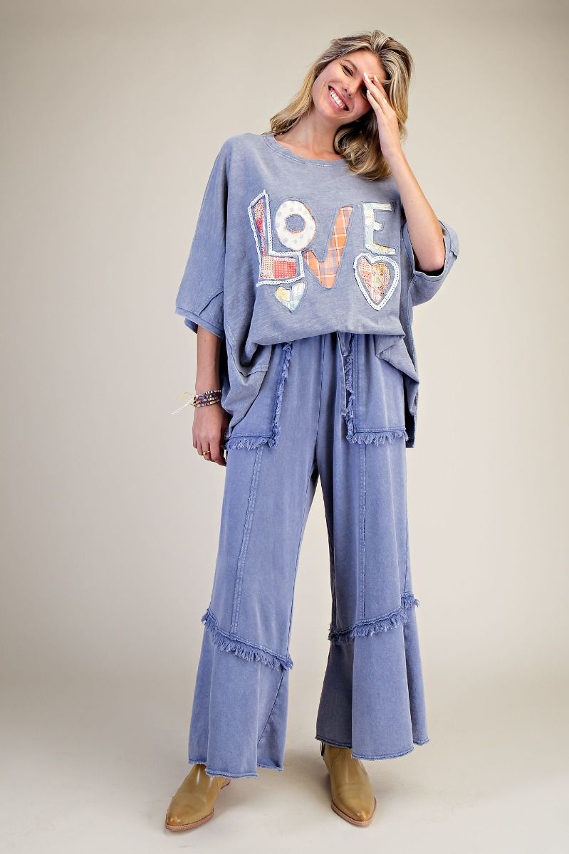 Woman wearing a blue outfit with 'LOVE' printed on it against a plain background