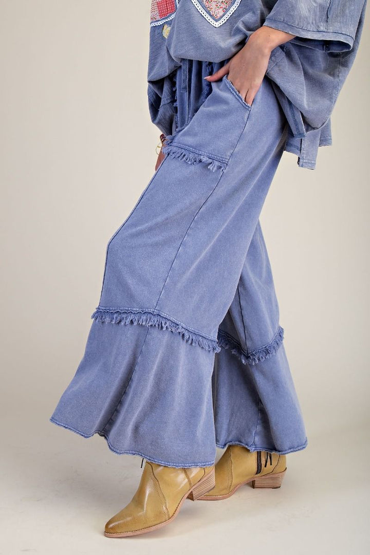 Denim pants with ruffled hem worn by a person on a plain background