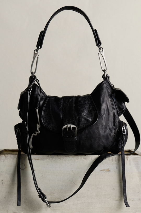 Black leather handbag on a light wooden surface with a neutral background