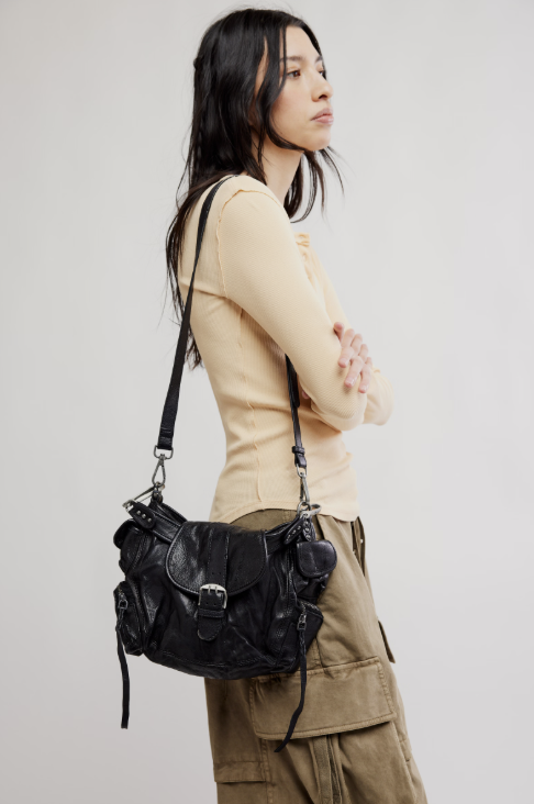 Woman carrying a black leather handbag against a plain background