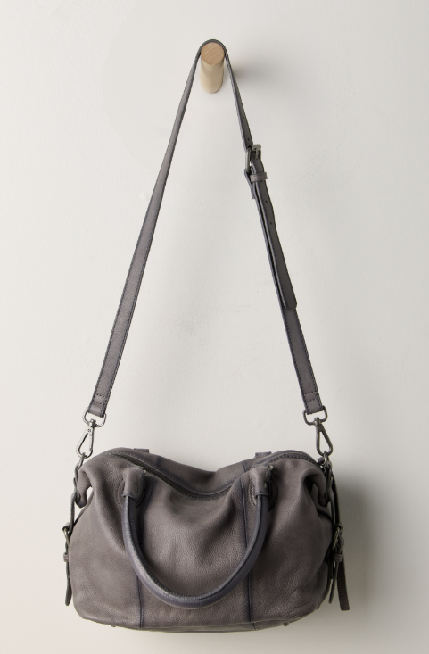 Grey purse hanging on hook on white wall