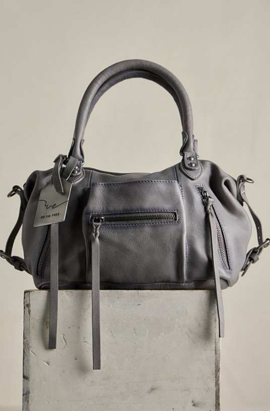 Grey purse sitting on concrete block on plain background