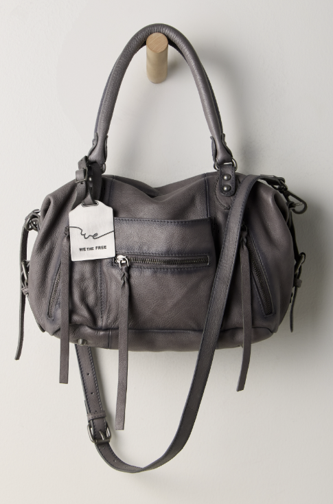 Grey purse hanging on hook on white wall