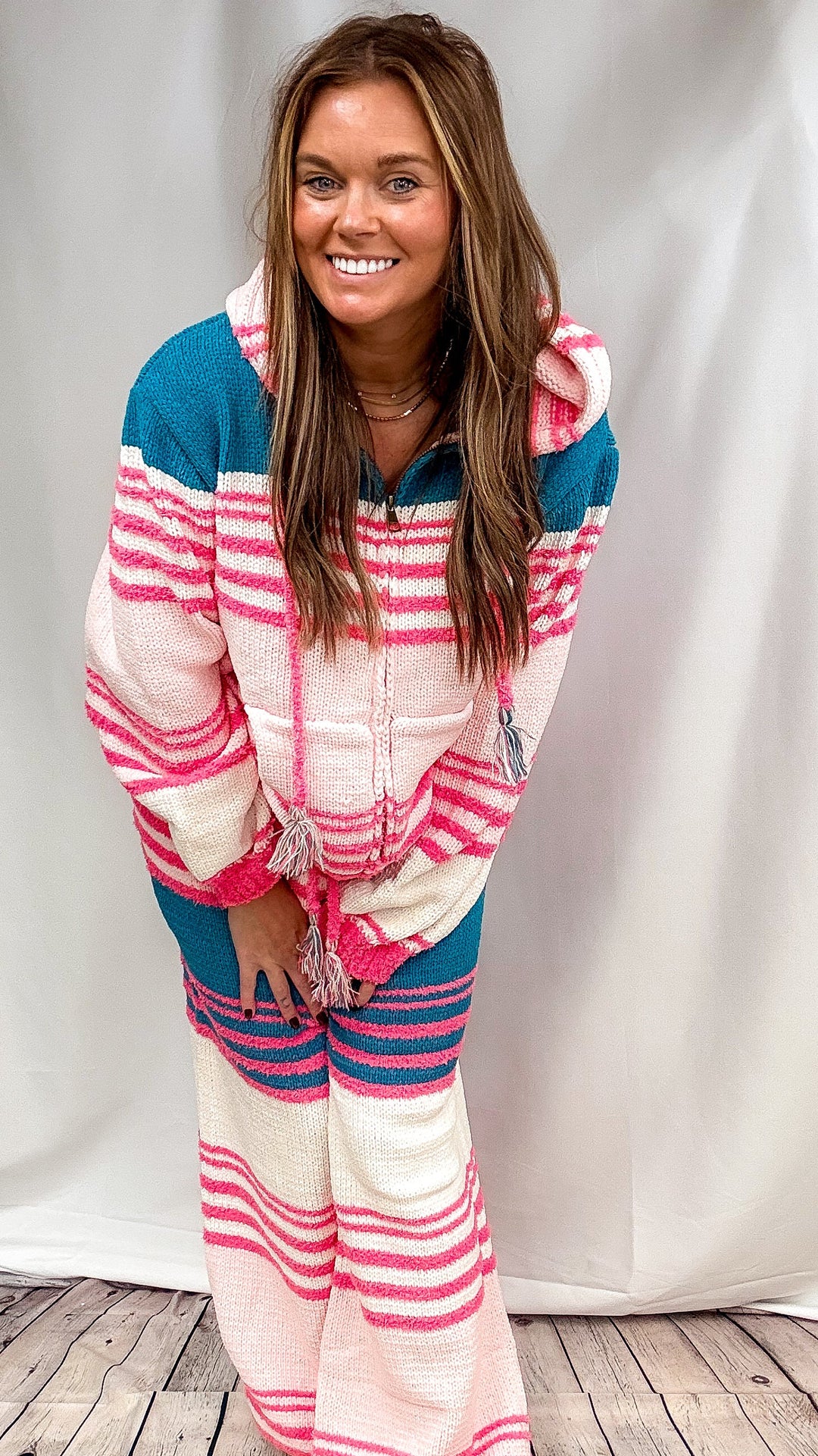 Woman wearing matching stripe set with pink, cream and teal stripes on plain background