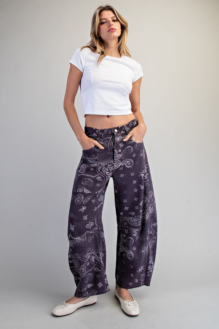 Woman wearing purple paisley jeans and white top on plain background