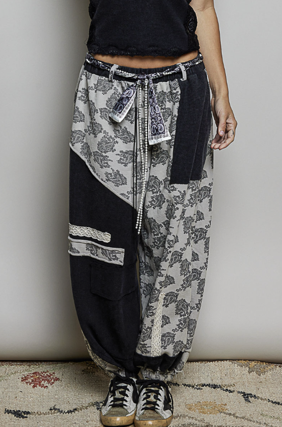 Woman wearing black tank top and black and white patch pants on plain background