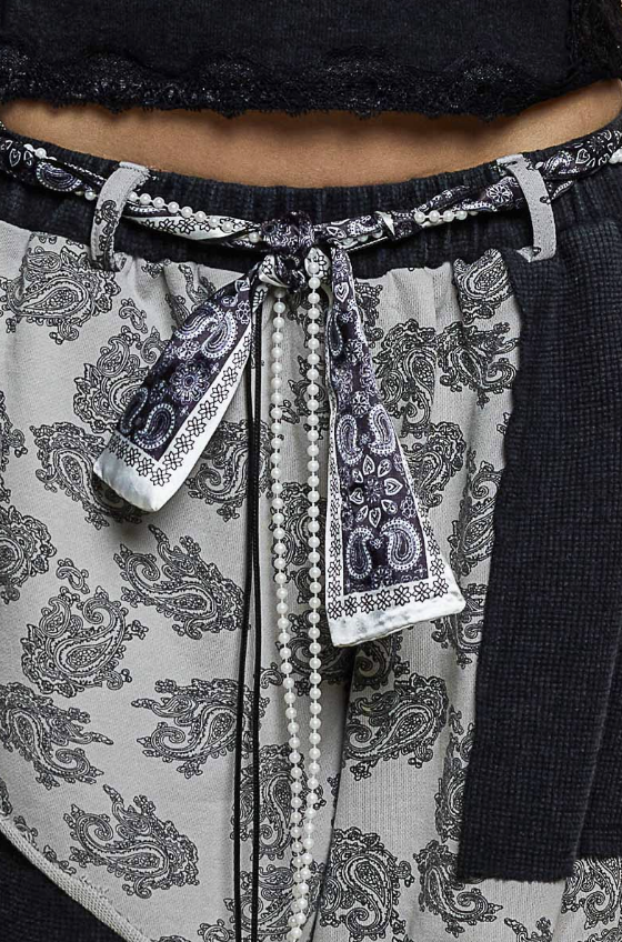 Close up of black and white patchwork pants with bandana and pearl belt