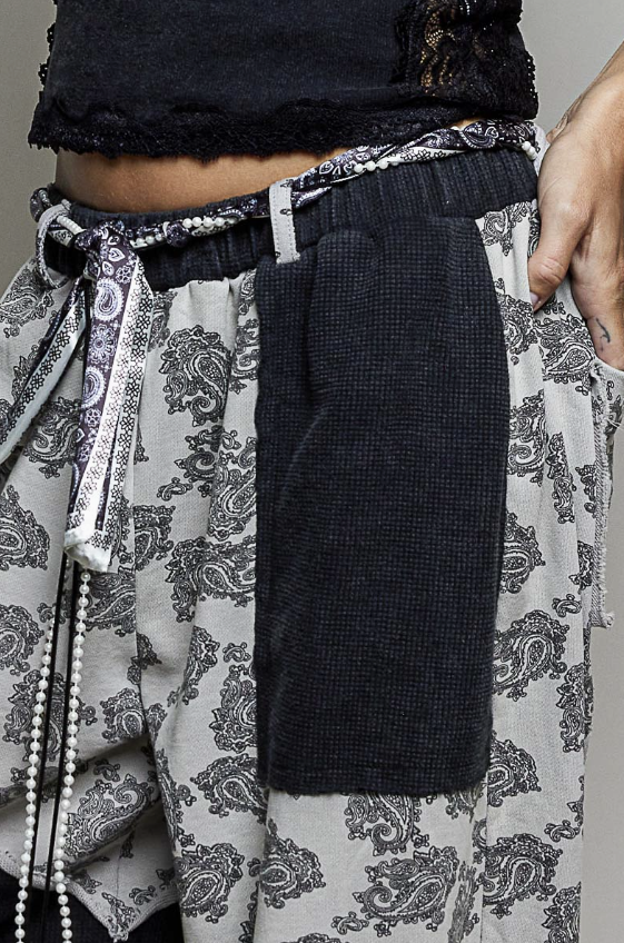 Close up of black and white patchwork pants with bandana and pearl belt