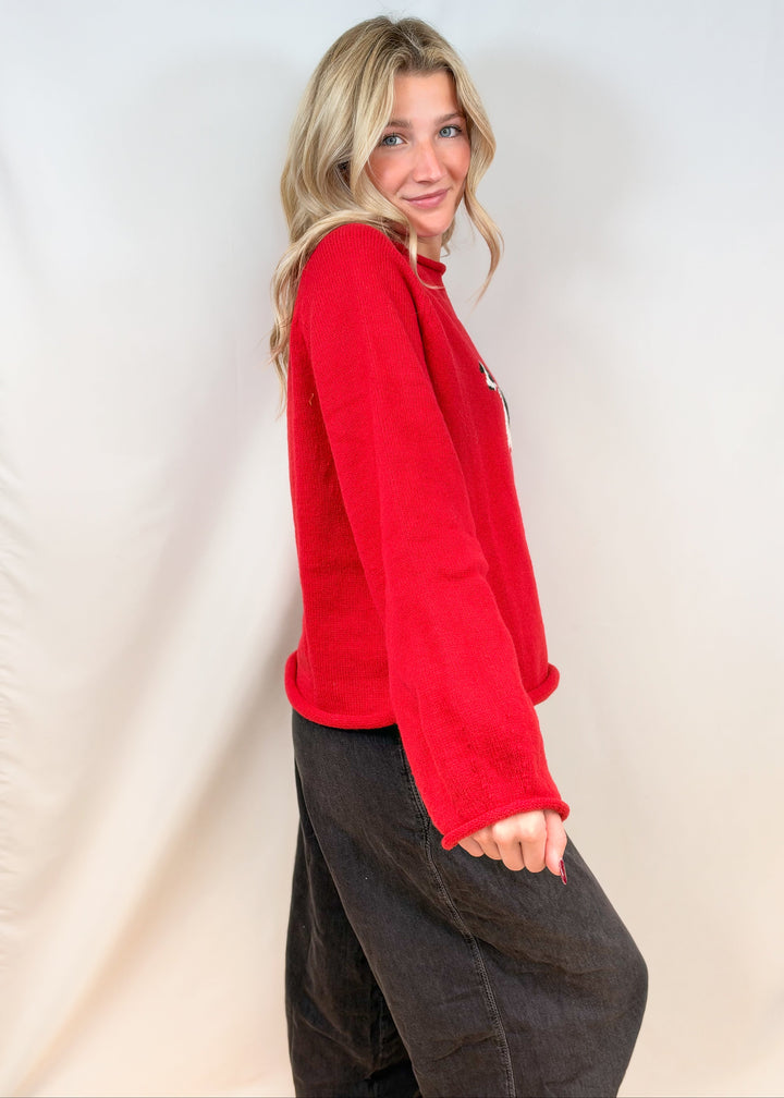 Woman shown from side view wearing red sweater and black pants on plain background