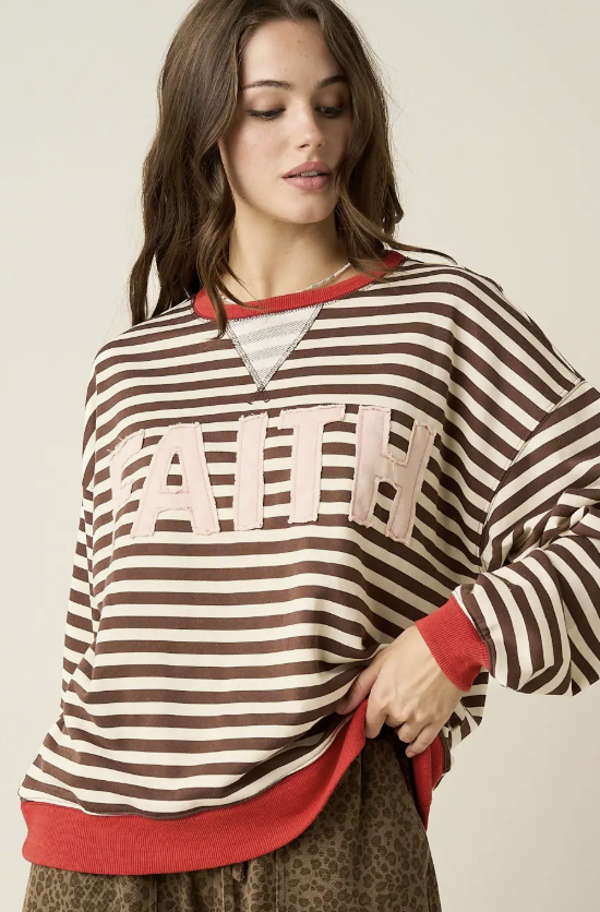 A woman wearing a brown and cream striped sweatshirt with &