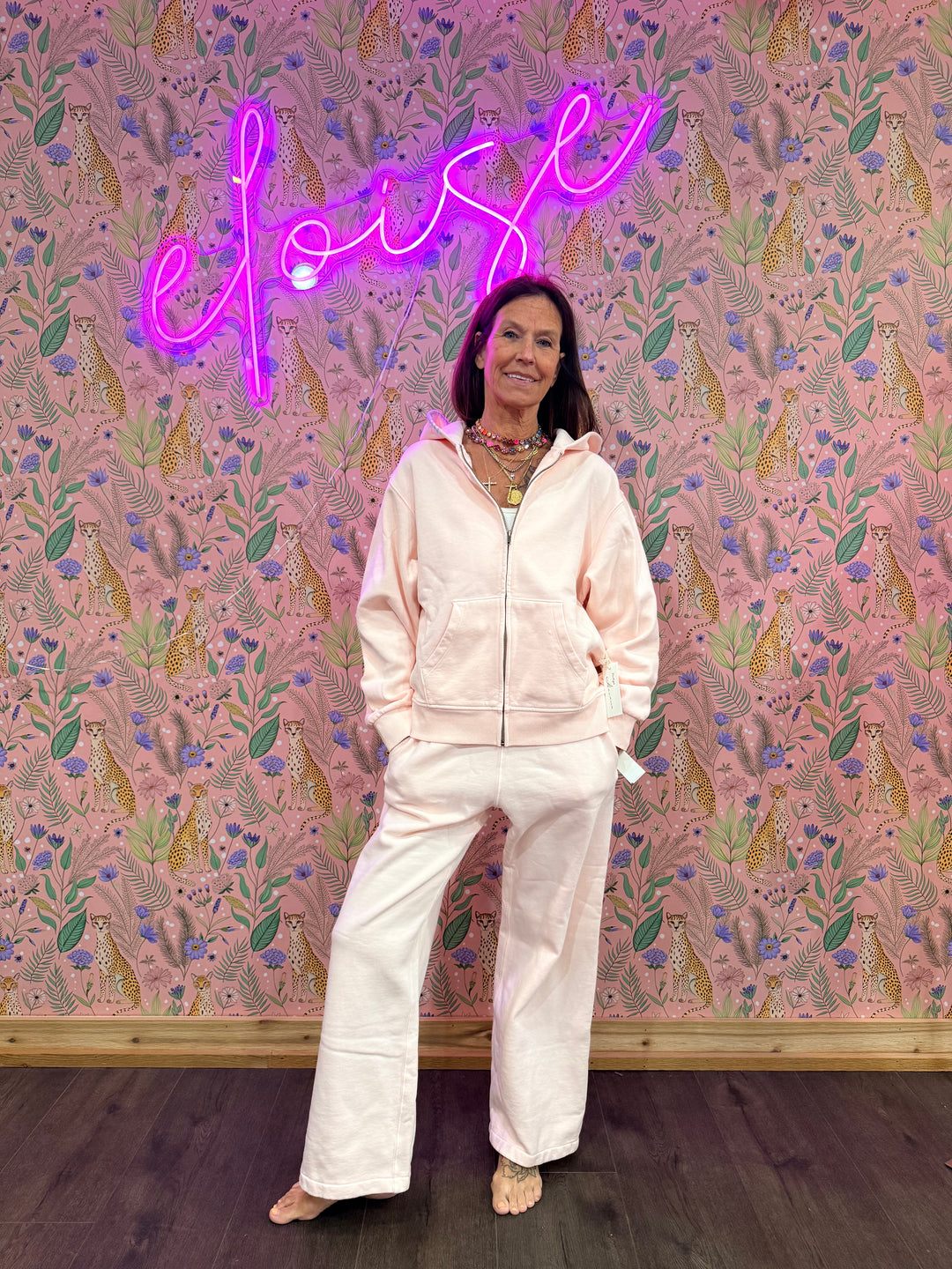 Woman wearing matching pink hoodie and sweatpants on pink floral background