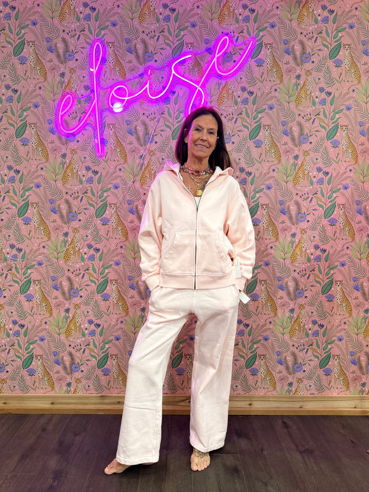 Woman wearing matching pink hoodie and sweatpants on pink floral background
