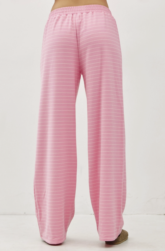 Pink wide-leg lounge pants with thin white horizontal stripes, shown from the back on a model against a white studio background.