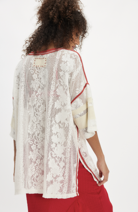 Woman wearing a white lace kimono-style top with red trim on a white background