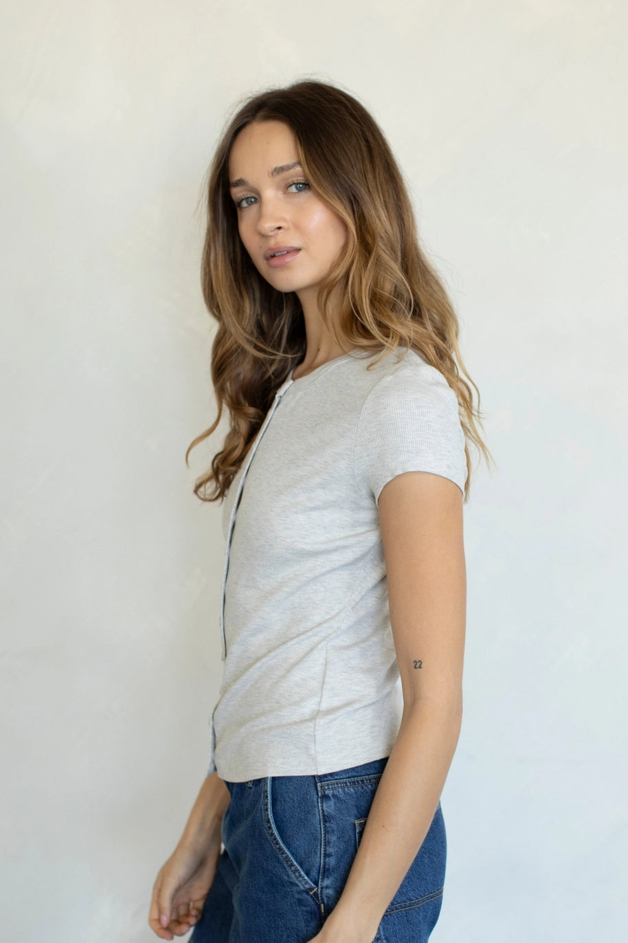 Woman wearing heather grey button up tee on plain background