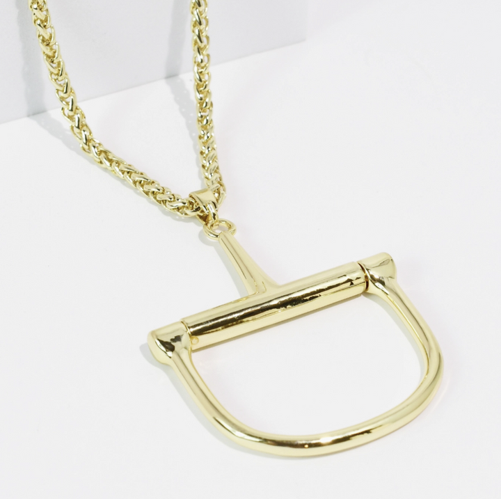 A gold-tone horsebit necklace with a thick curb chain, displayed on a clean white background.
