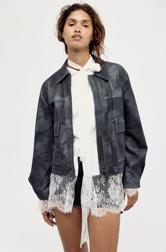 A model wearing a dark washed denim jacket over a white blouse and a white lace shirt, styled with black shorts against a plain white studio background.