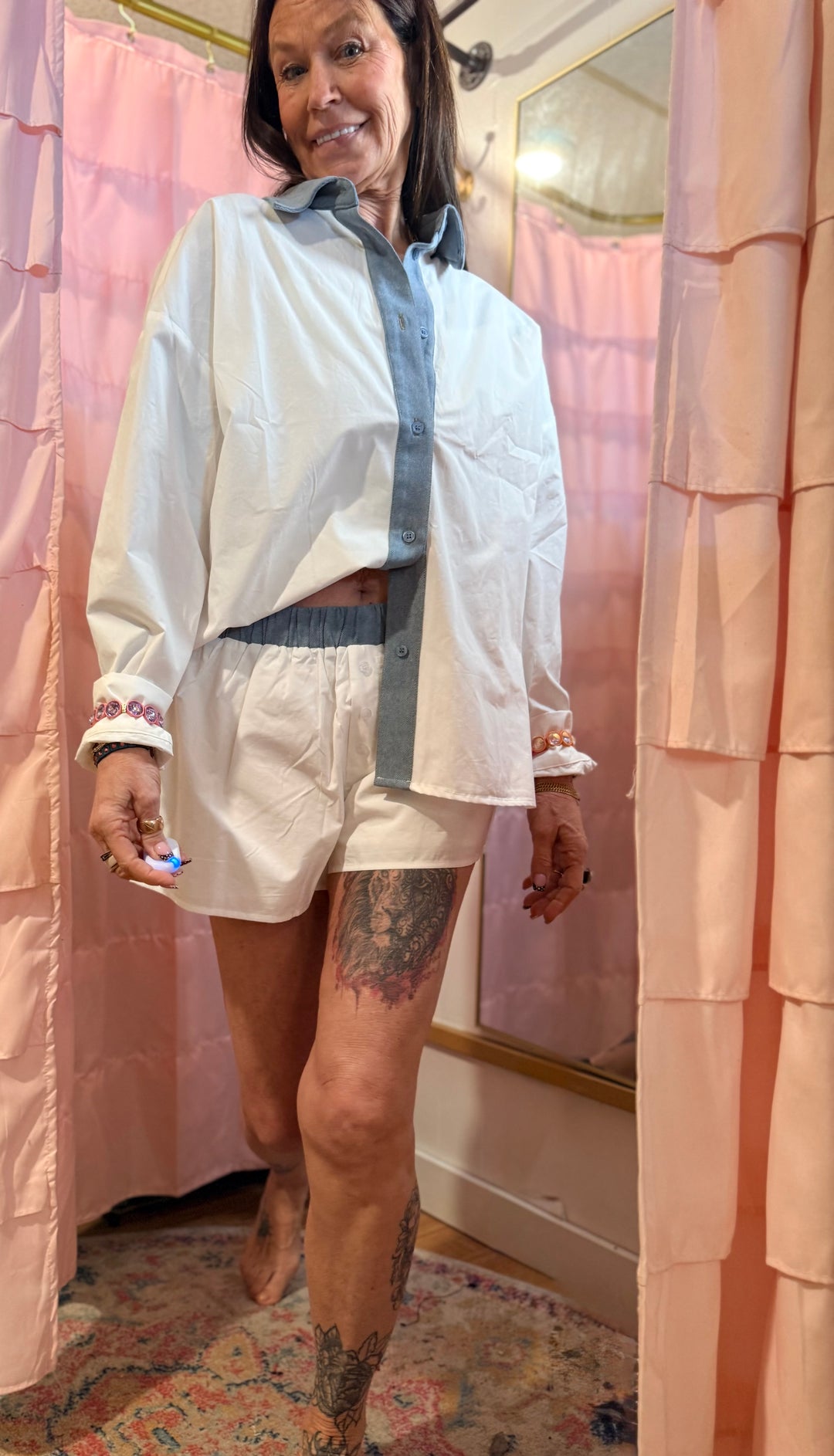 Person wearing a white shirt and shorts standing in front of a pink shower curtain.