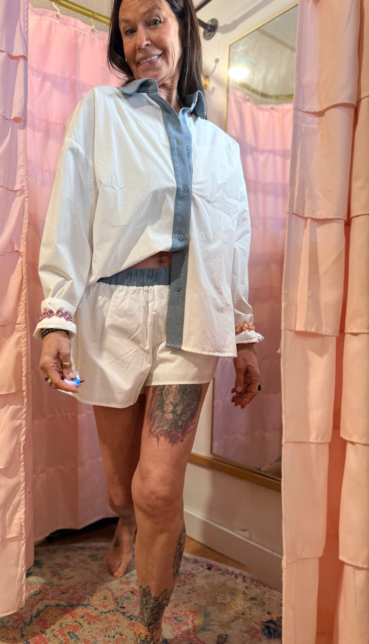 Person wearing a white shirt and shorts standing in front of a pink shower curtain.
