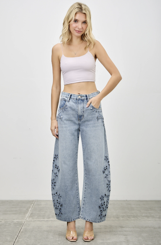 Woman wearing light blue jeans and a pink top on a plain background