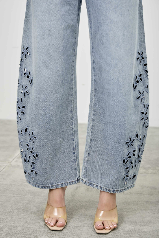 Light blue jeans with floral embroidery on a neutral background
