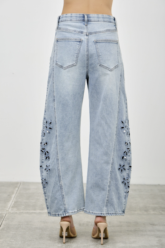 Light blue jeans with floral cutouts on a plain background