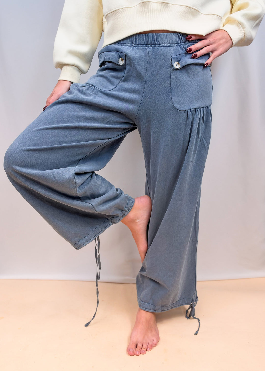 Woman shown from waist down wearing blue cinch hem pants on plain background