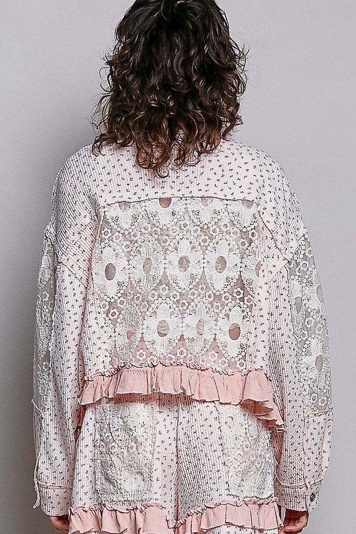 Person wearing a floral blouse with ruffled layers on a plain background