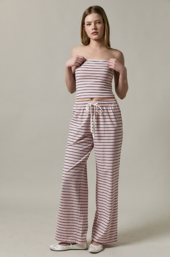 Woman wearing a striped strapless top and wide-leg pants against a neutral background