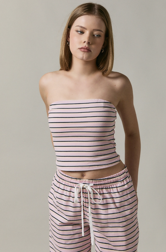 Woman wearing a striped strapless top and pants against a neutral background