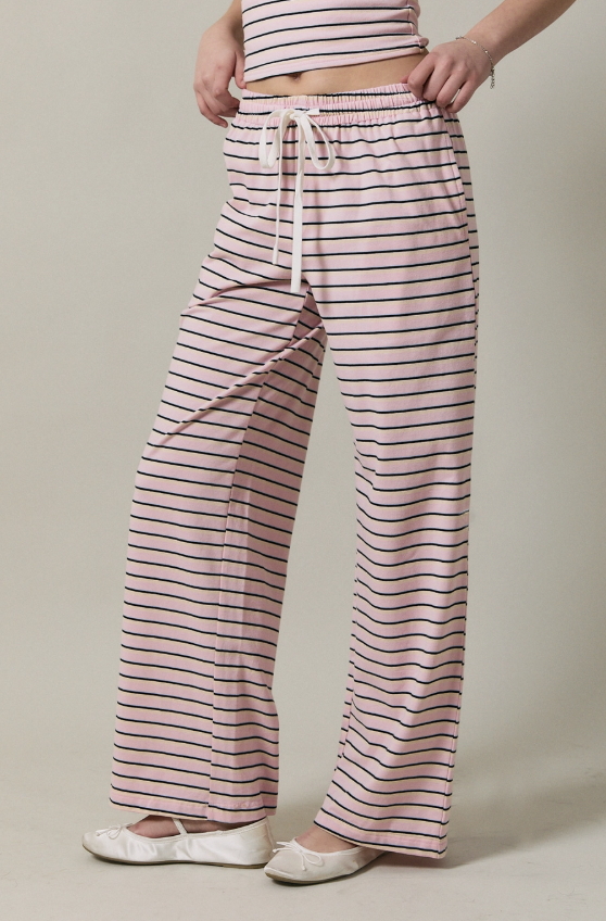 Person wearing pink and black striped pants with a plain background