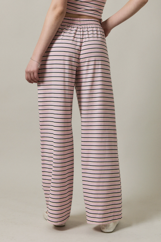Person wearing pink and black striped pants on a beige background