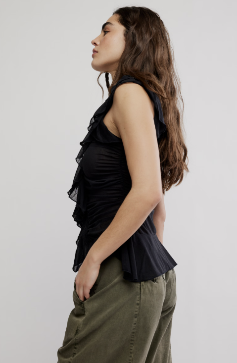 Woman wearing a black sleeveless top and green pants on a white background