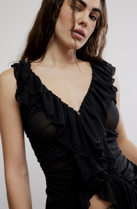 Woman wearing a black ruffled dress against a plain background