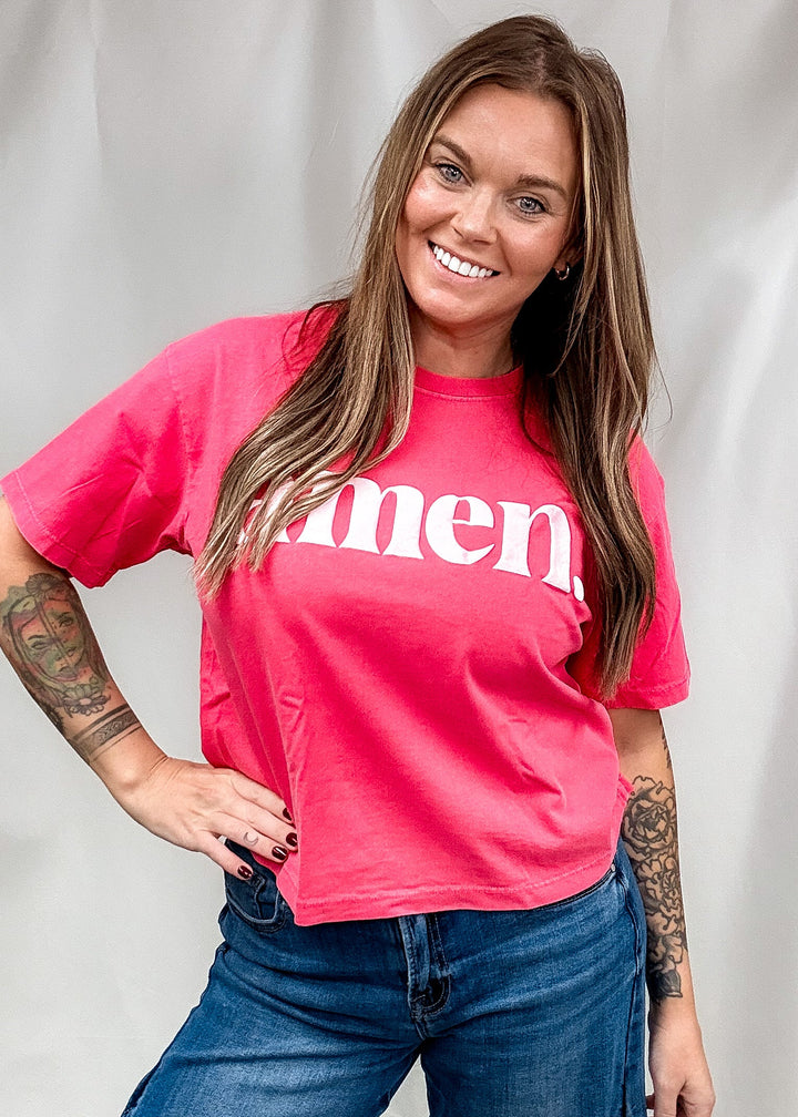 A woman wearing a bright pink cropped t-shirt with the word &