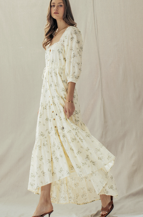 Woman wearing a white floral dress against a plain background