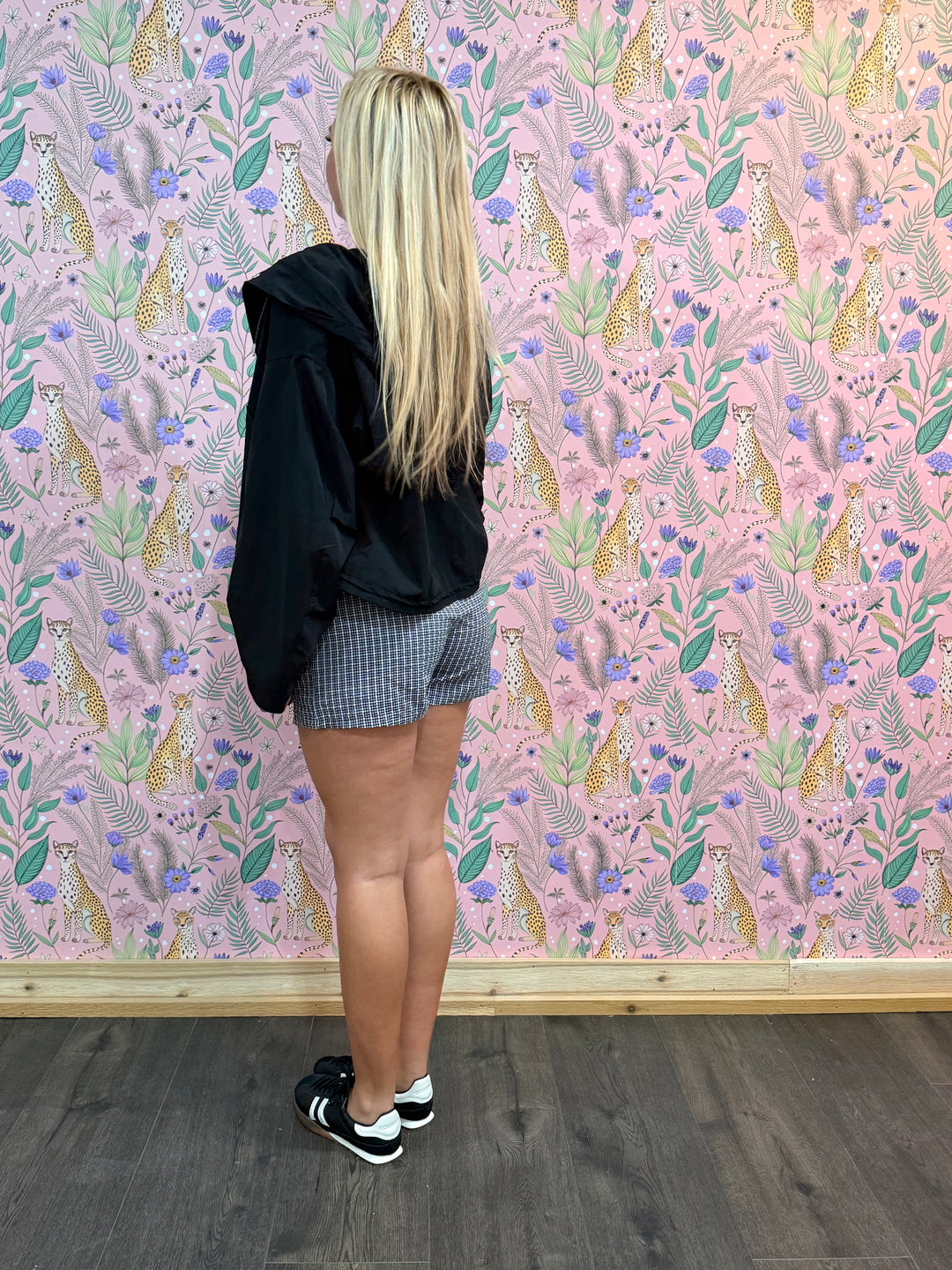 Person standing in front of a wall with a colorful animal pattern