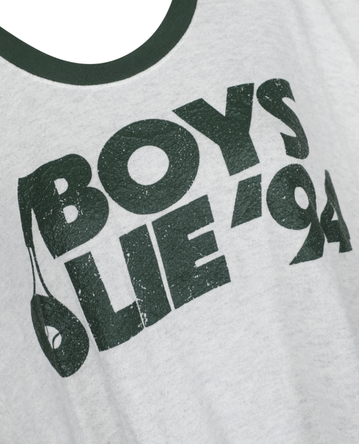 Close-up of a light heather gray t-shirt featuring a distressed dark green graphic print that reads &