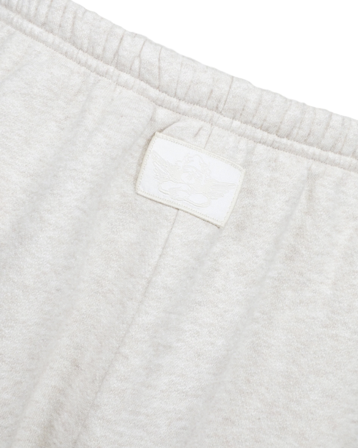 Close-up of light heather gray sweatpants showing the elastic waistband and a small tonal embroidered logo patch.