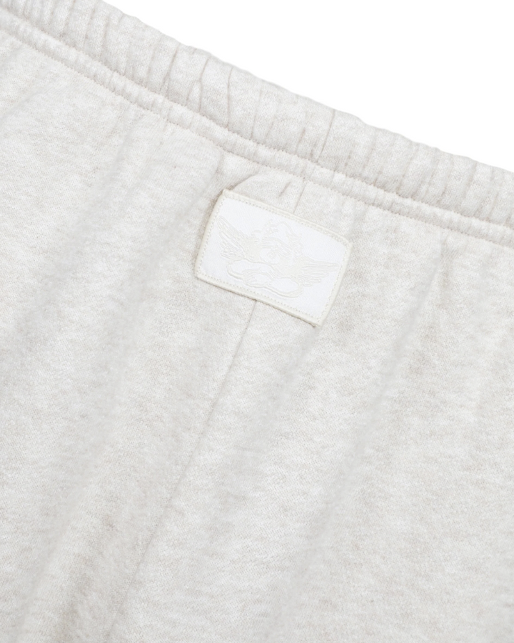 Close-up of light heather gray sweatpants showing the elastic waistband and a small tonal embroidered logo patch.