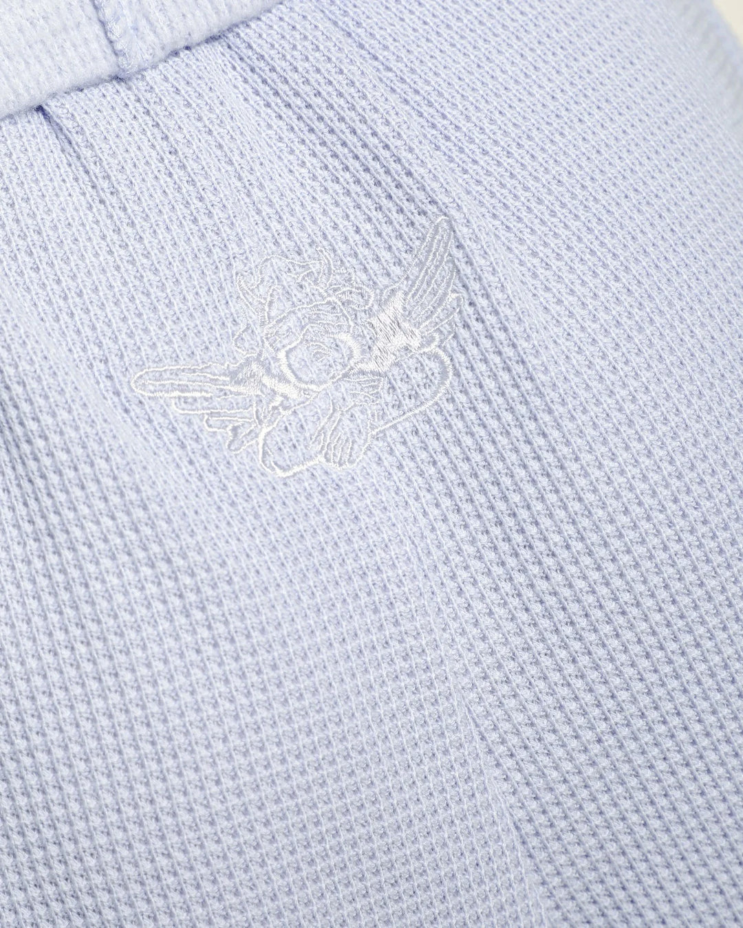 Close-up of a light blue fabric with an embroidered logo.