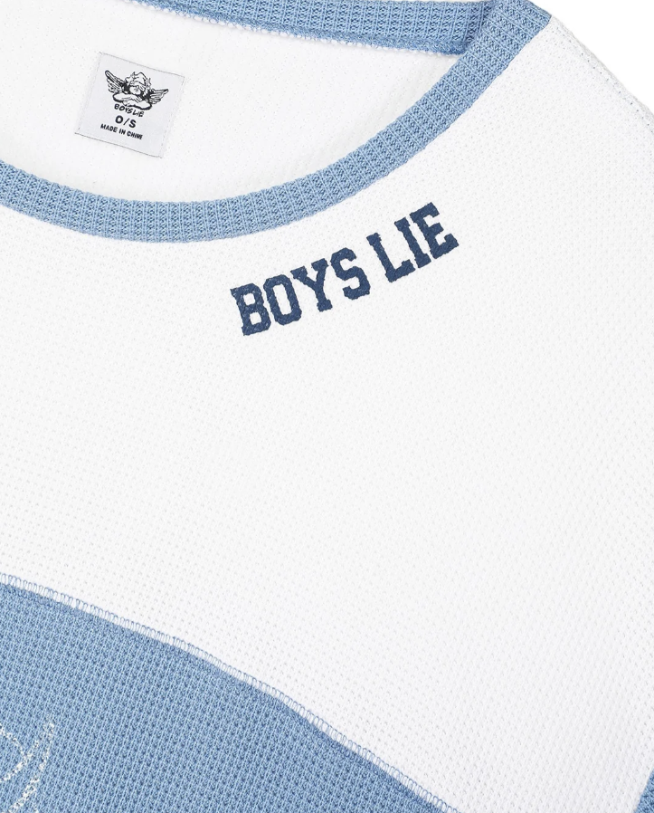 Close-up of a white knit top with light blue trim and a navy embroidered &