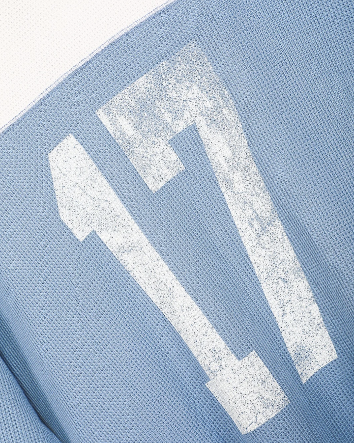 Close-up of a light blue knit fabric with a large distressed white number 17 graphic.