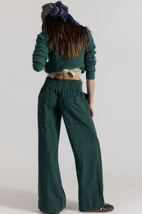 Woman shown from back wearing dark green denim pants and matching sweater on white background