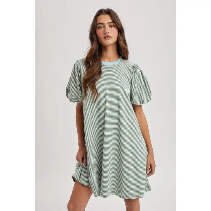 Woman wearing green striped dress with blue detail on plain background