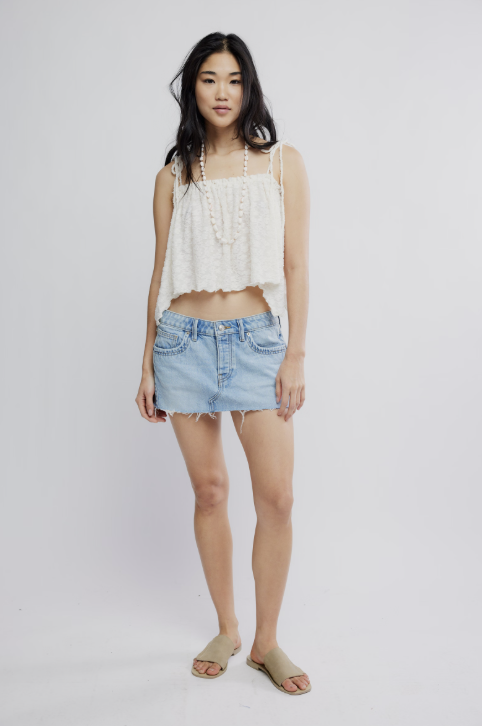 Woman wearing a white top and denim skirt on a plain background