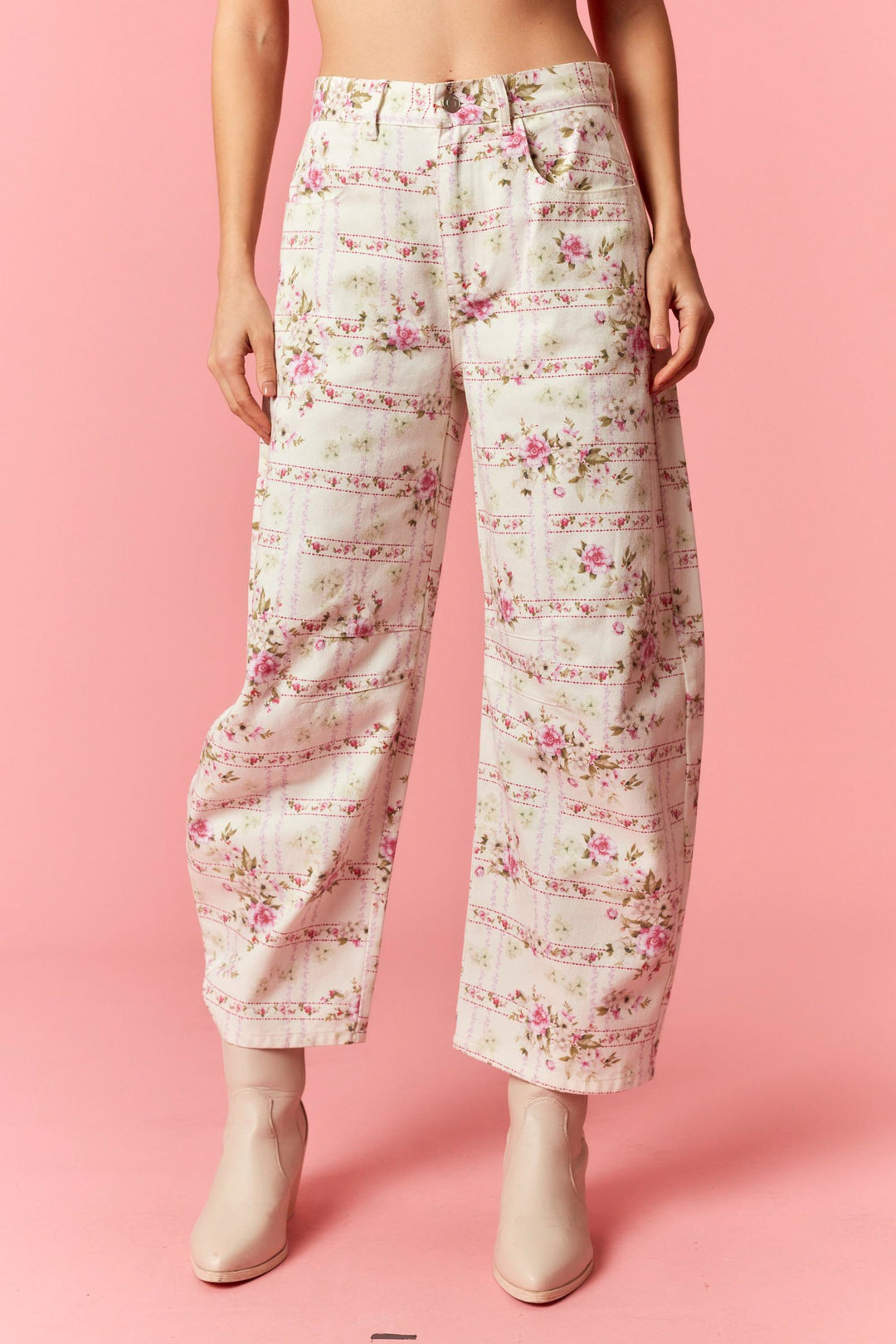 Floral patterned pants worn by a person on a pink background