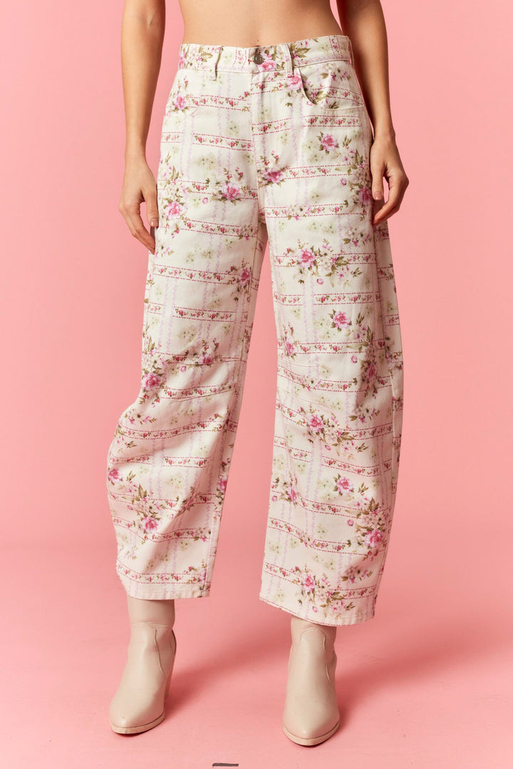 Floral patterned pants worn by a person on a pink background